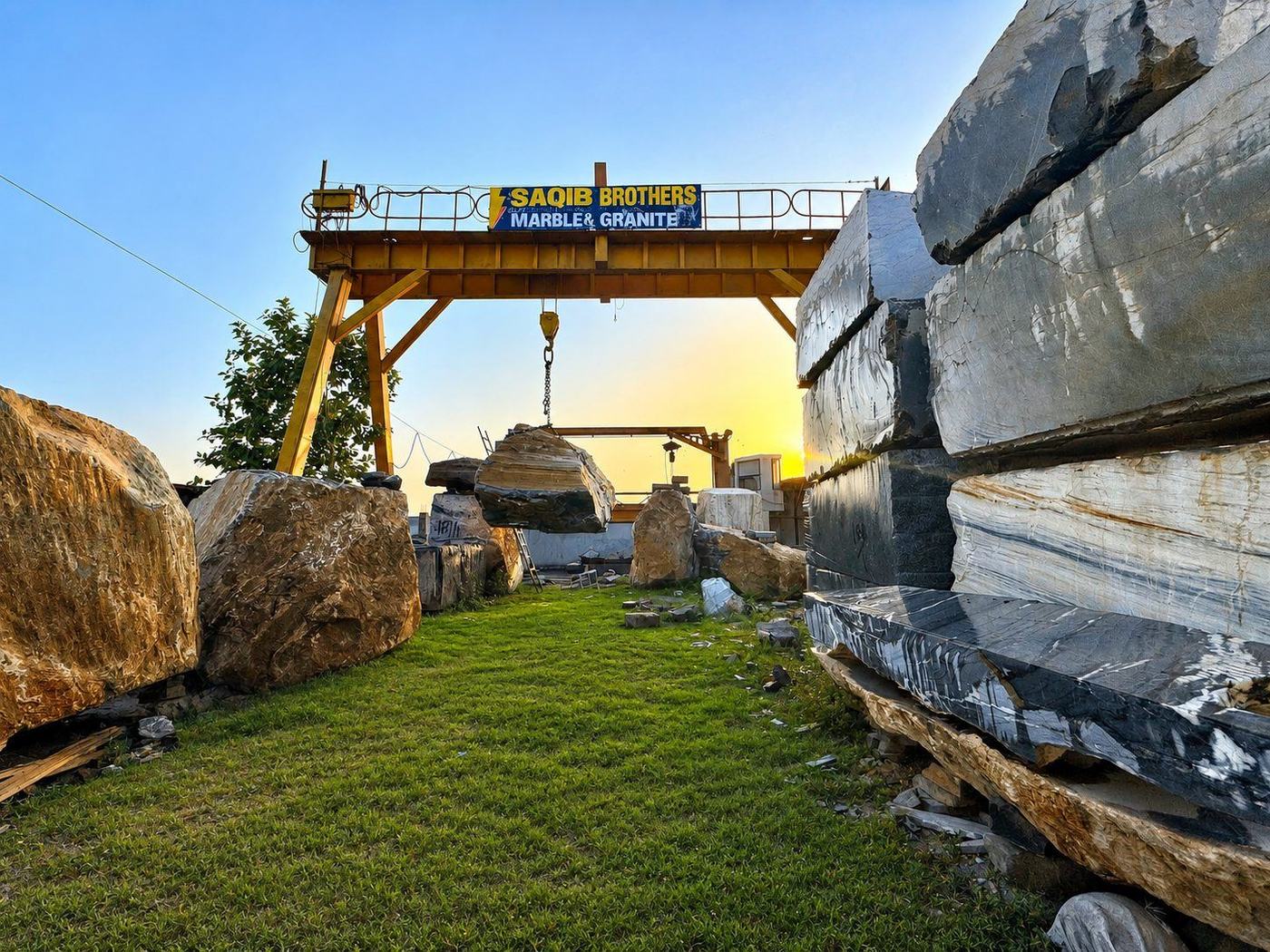Saqib Brothers yard — gantry crane over raw marble blocks at sunset